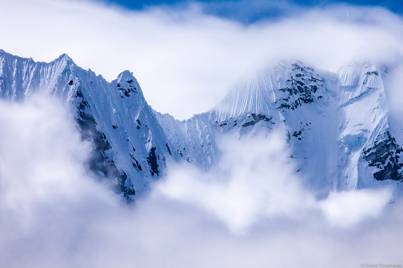 A rugged ridge in the Cordillera Huayhuash appears briefly from the clouds late at night.