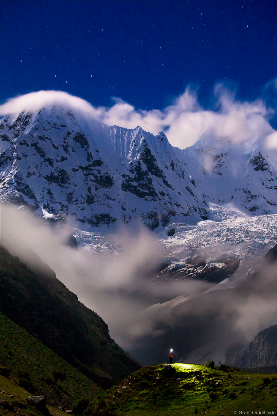 A lone trekker under the night sky in the rugged Cordillera Huayhuash mountain range.