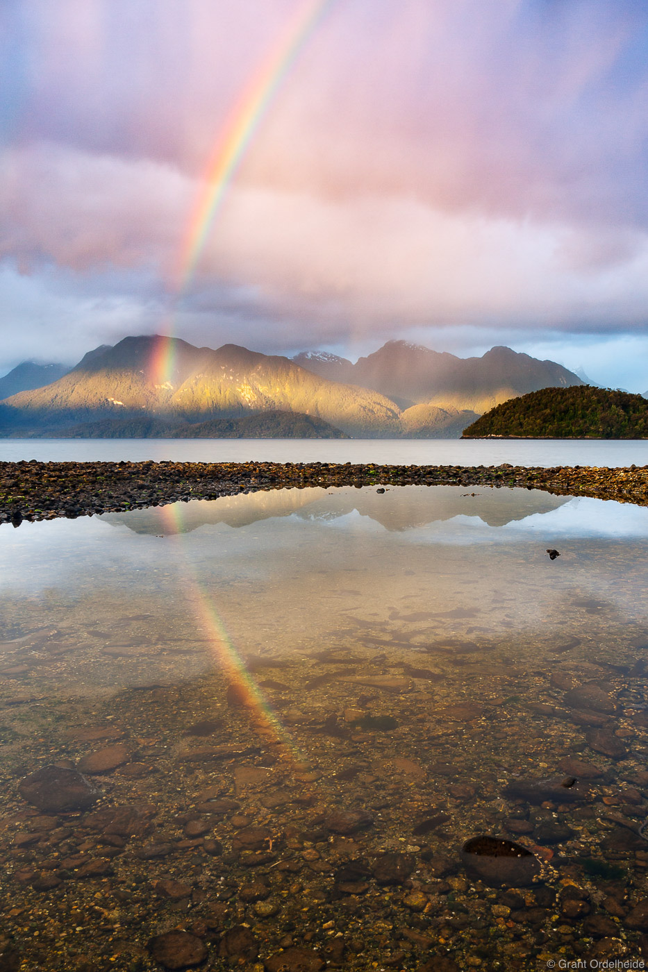 Light breaks through the storm illuminating a rainbow on the Cisnes Channel near Puerto Cisnes in Chile.