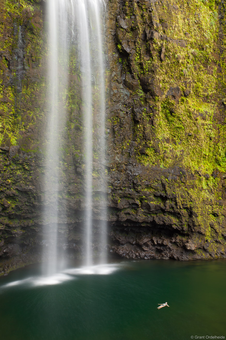 A hiker cools off under the three hundred foot&nbsp;Hanakapi'ai falls&nbsp;along the Kalalau trail on Kauai's Na Pali coastline...