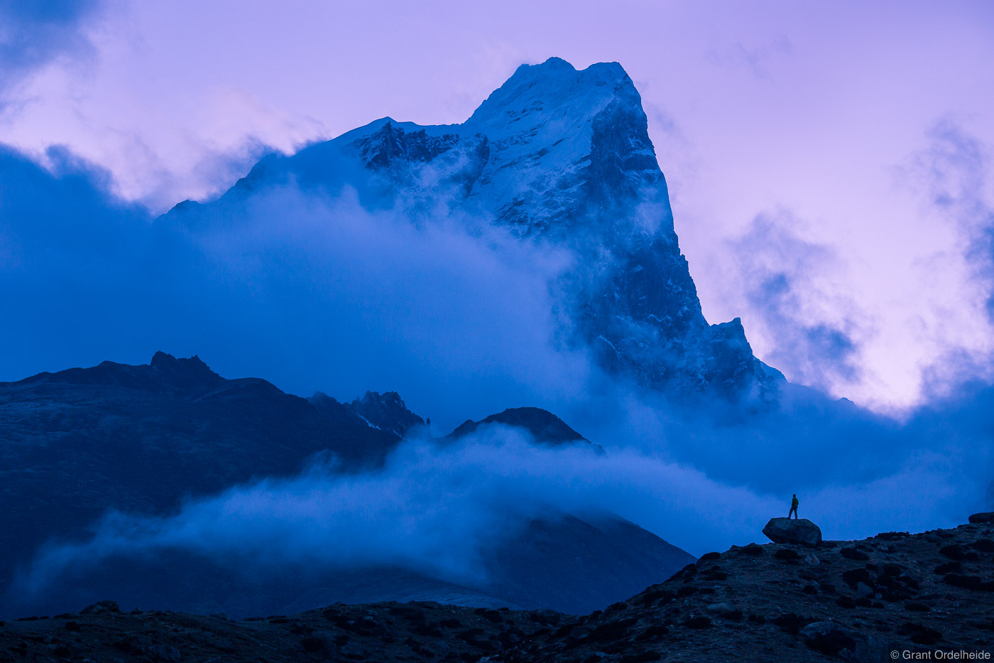 A silhouetted figure gives scale to the massive mountain Taboche as night falls in the Himalaya.