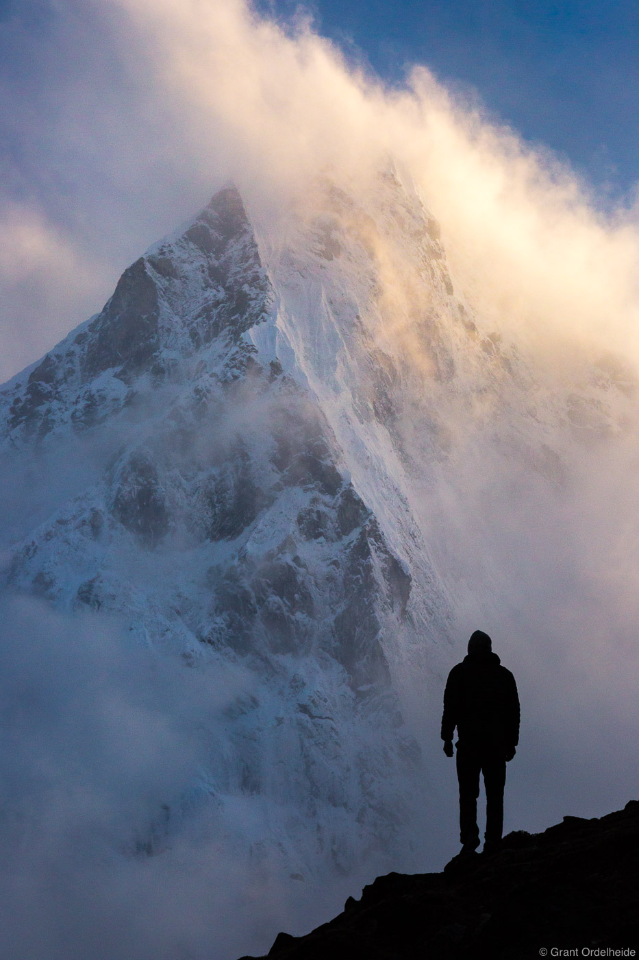 A lone figure stands in front of a clearing storm on Cholatse in the Everest Region of Nepal.