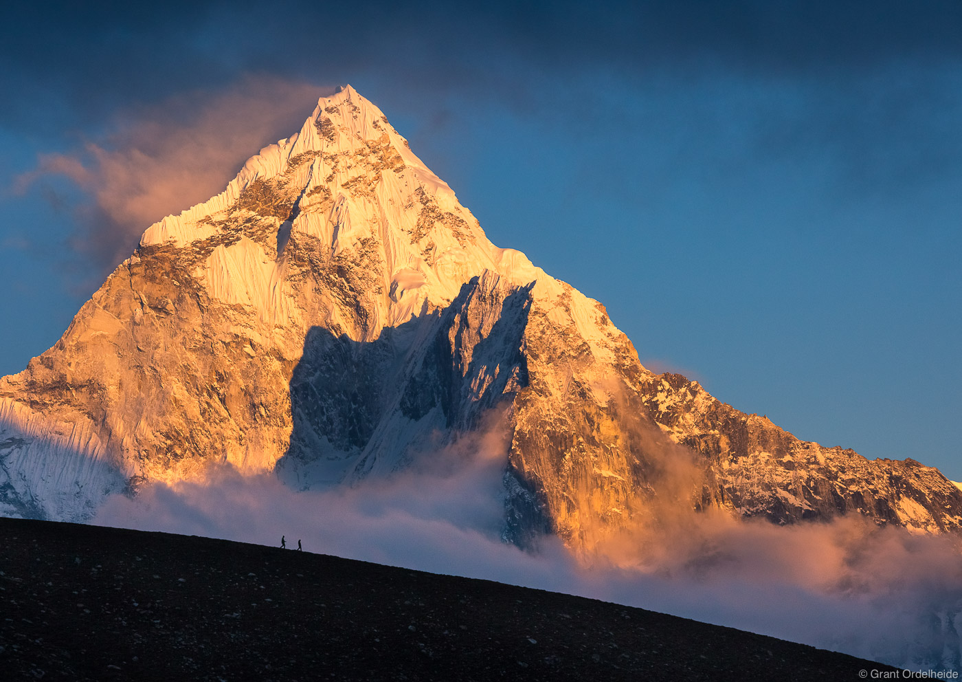 Two figures shrink in front of the massive Ama Dablam in Nepal's Everest Region.