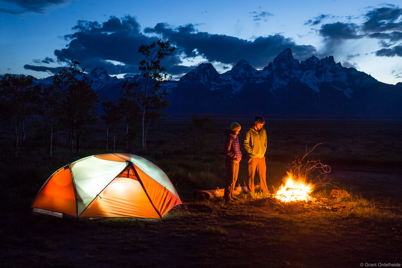 Friends enjoying a fire near camp under the Tetons.