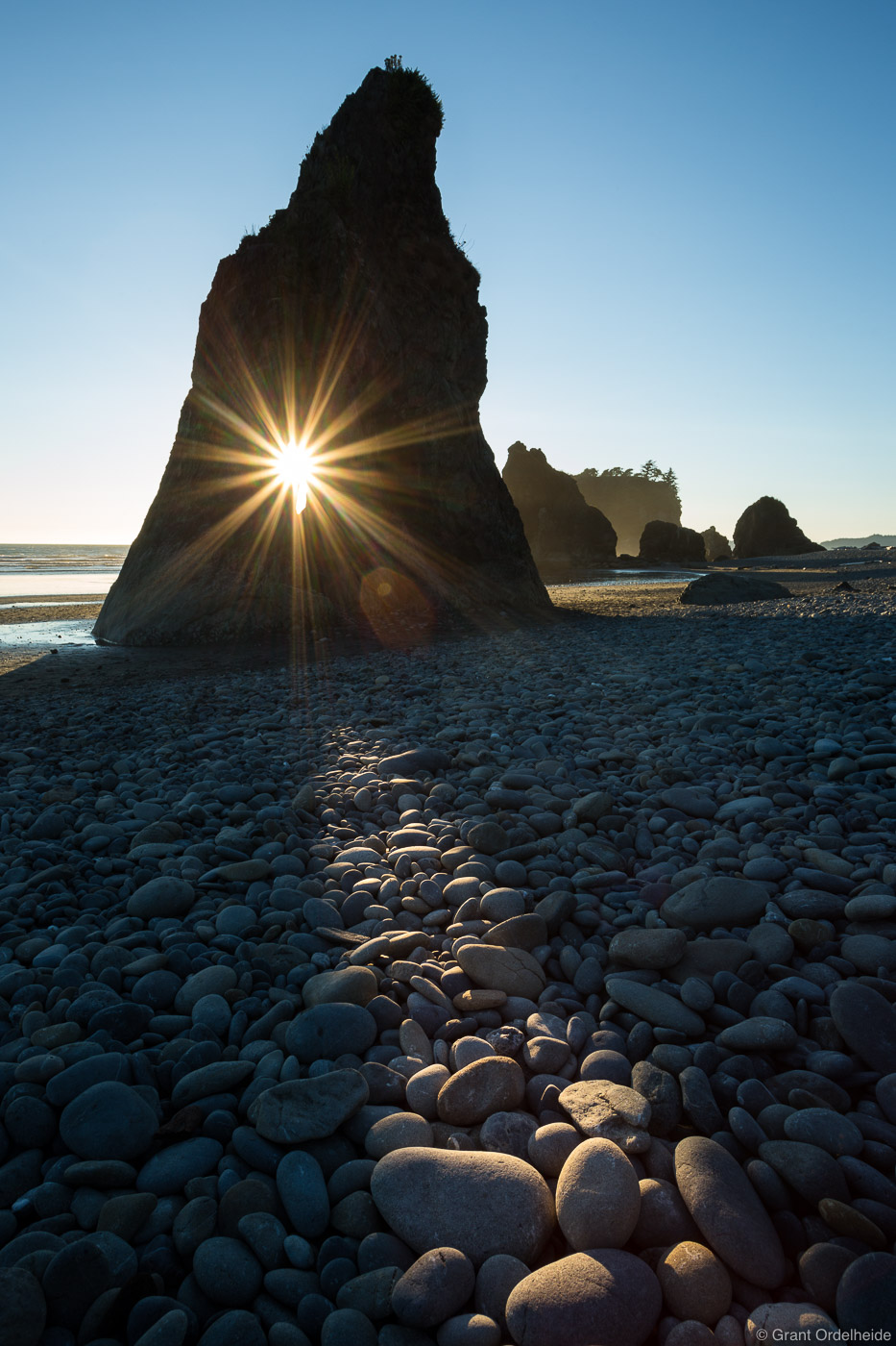 The sun sets through a hole in a seastack on Ruby Beach in Washington's Olympic National Park.