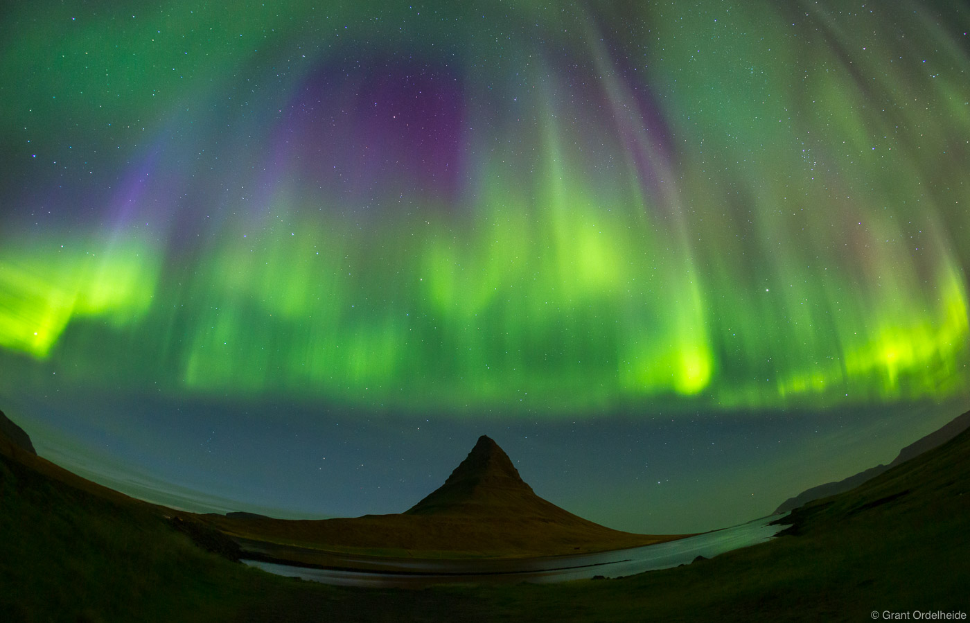 A colorful curtain of Aurora Borealis descends over Kirkjufell mountain on the&nbsp;Snæfellsnes peninsula in western Iceland...