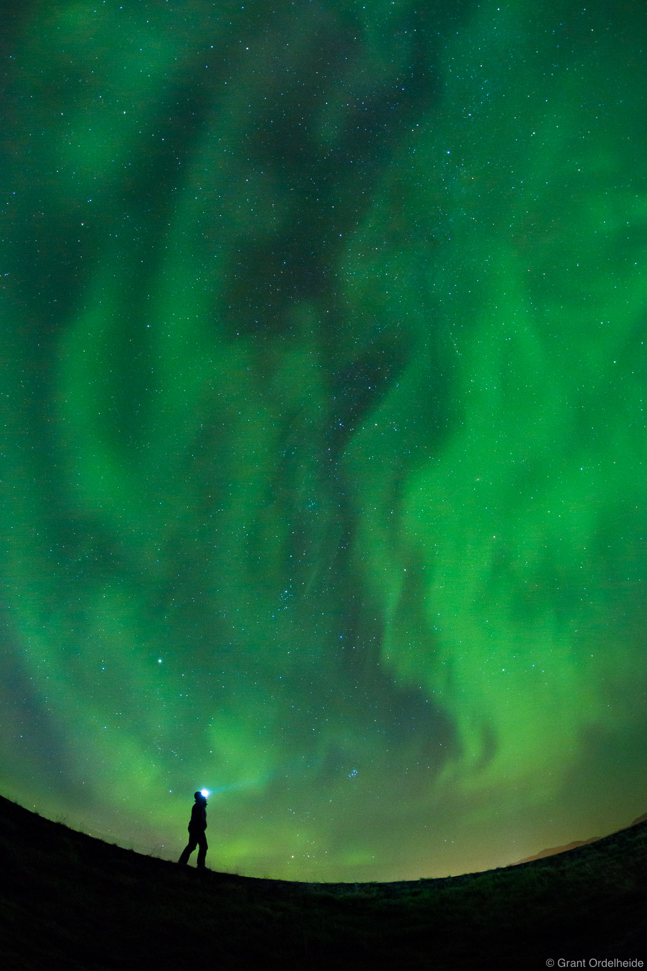 A young&nbsp;woman admires the dancing northern lights above near&nbsp;Grundarfjörður, Iceland.