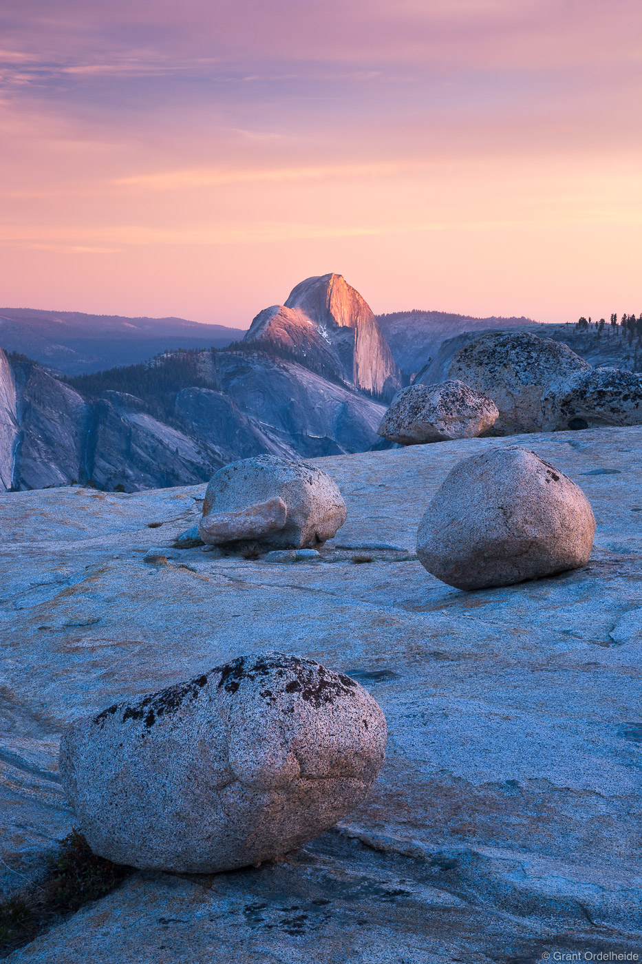 Sunset on Half Dome with glacier erratics on polished granite near Olmstead Point.