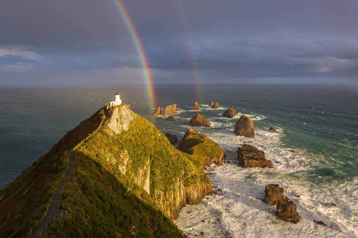A rainbow over the Nugget Point Lighthouse along the coast of New Zealand's South Island.
