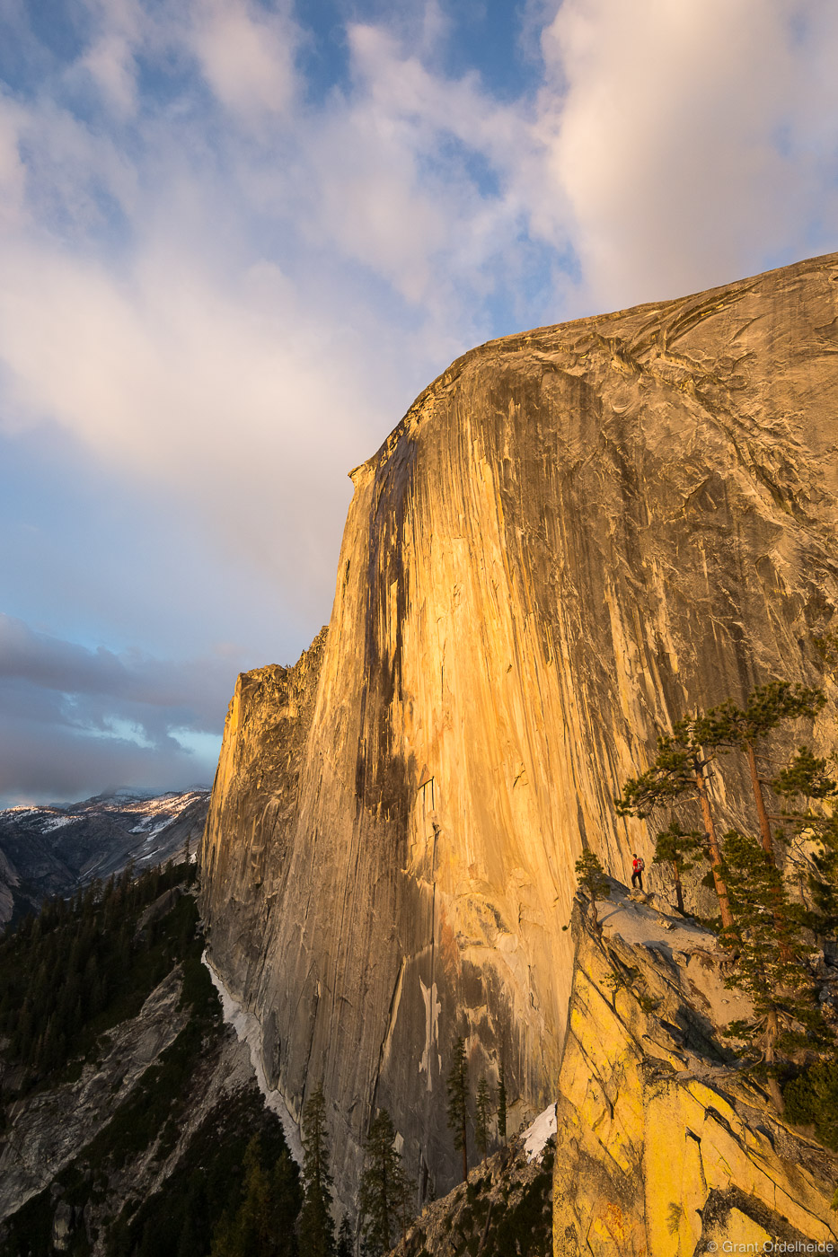 A hiker looking out over the monolithic northwest face of Half Dome in California's Yosemite National Park.