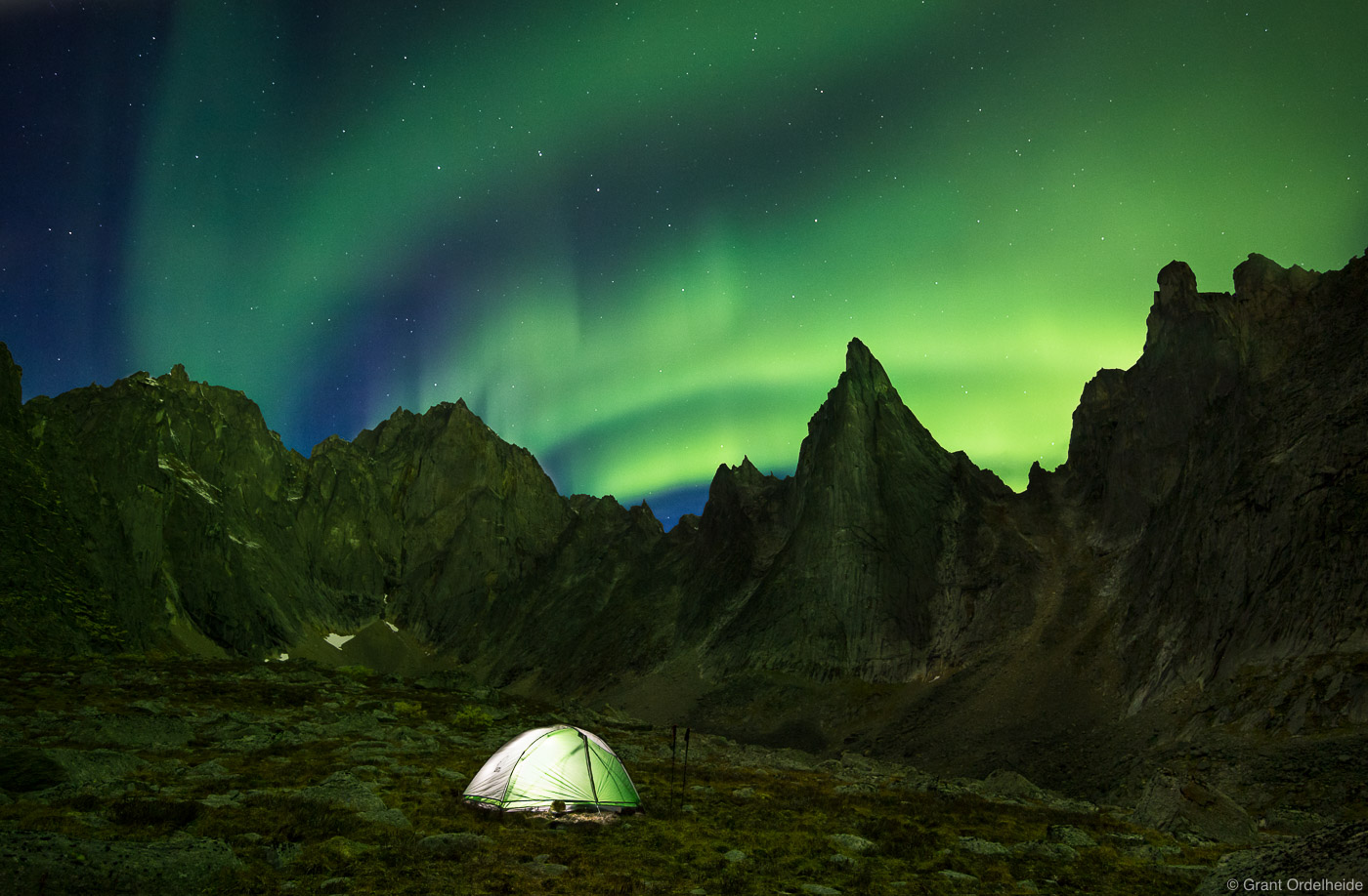An illuminated tent under the aurora borealis in a remote valley in Tombstone Territorial Park.