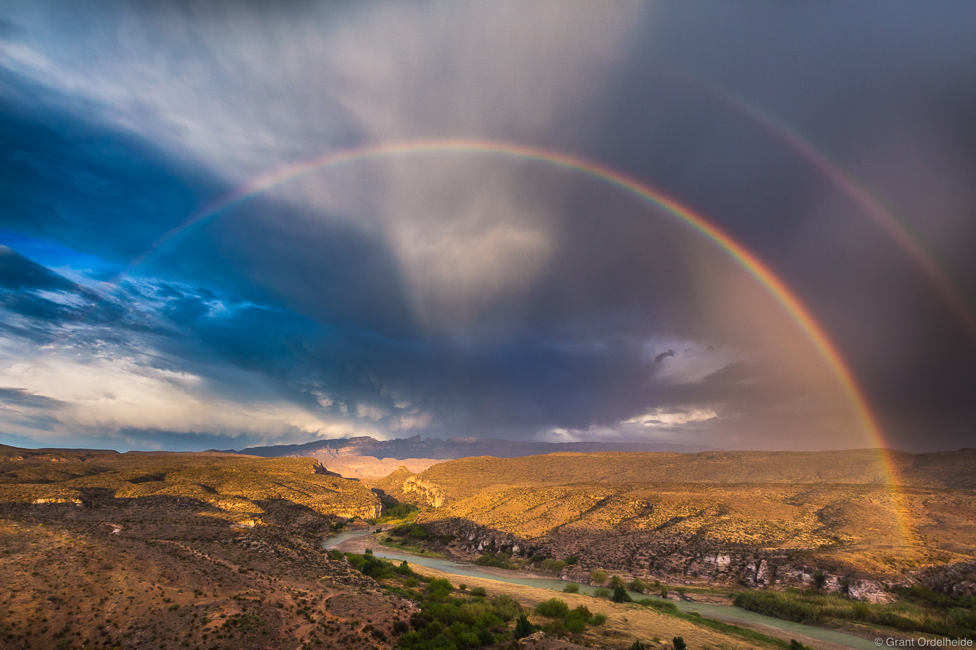 A full rainbow over the Rio Grande river, which serves as the USA/Mexico border, and the Sierra del Carmen Mountains viewed from...
