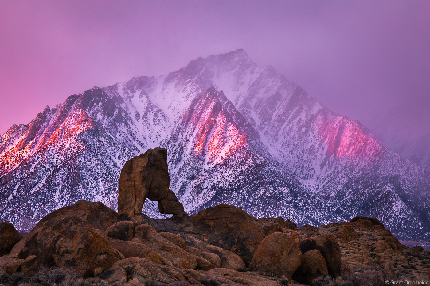 A stormy sunrise over Lone Pine peak and a remote arch in the Alabama Hills.