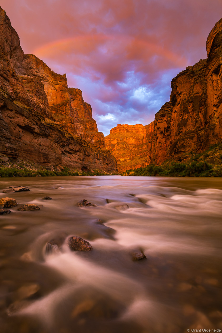 A stormy sunset and rainbow over the Colorado River near Fern Glen Canyon in Grand Canyon National Park.
