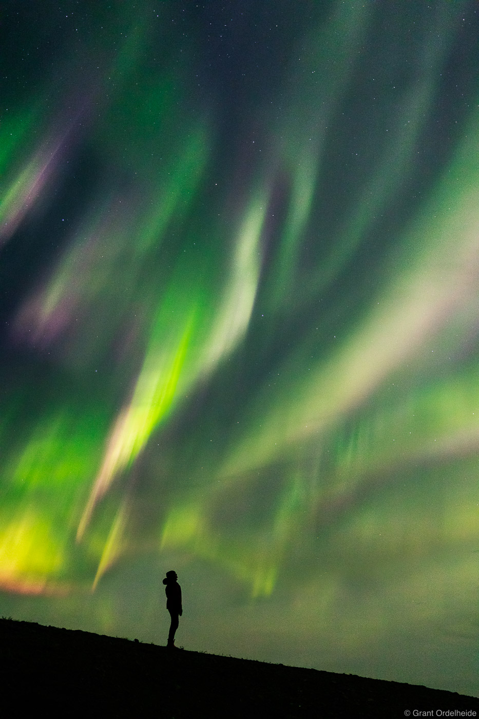 A person below a spectacular display of Aurora Borealis in northern Canada.