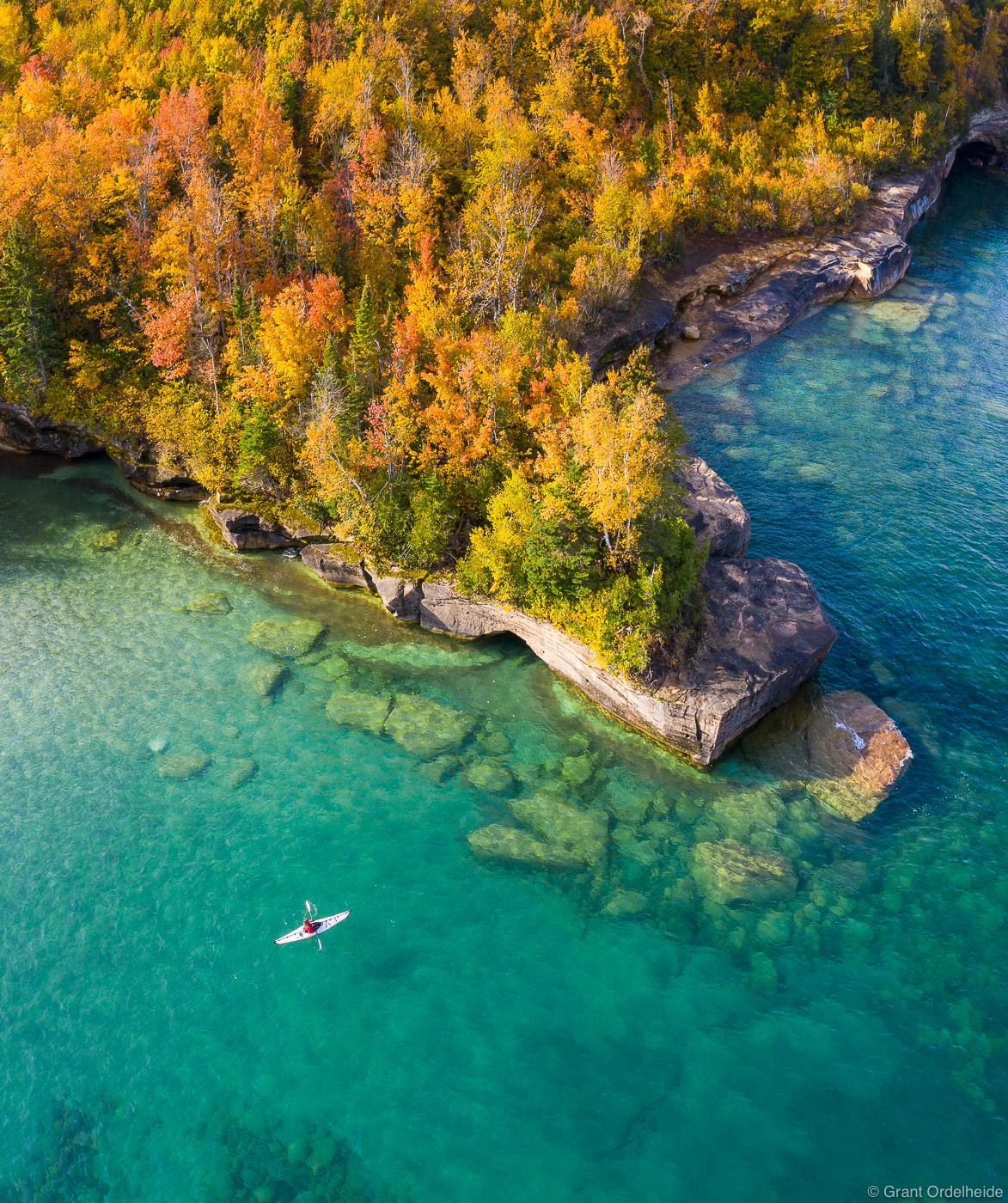 A kayaker paddling on the clear waters of Lake Superior along Michigan's Upper Peninsula.