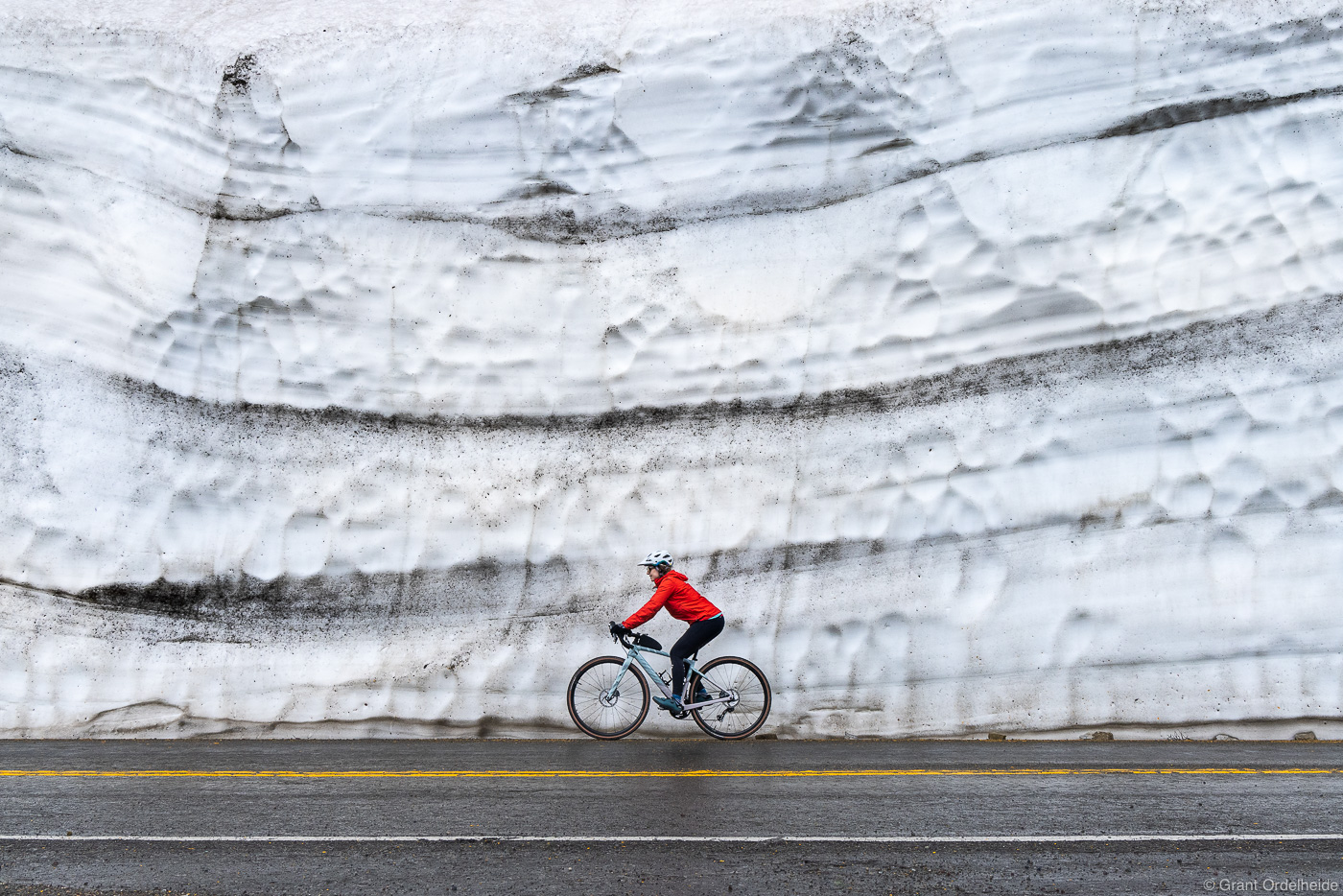A cyclist riding past spring snow drifts on Glacier's famous Going to the Sun road.