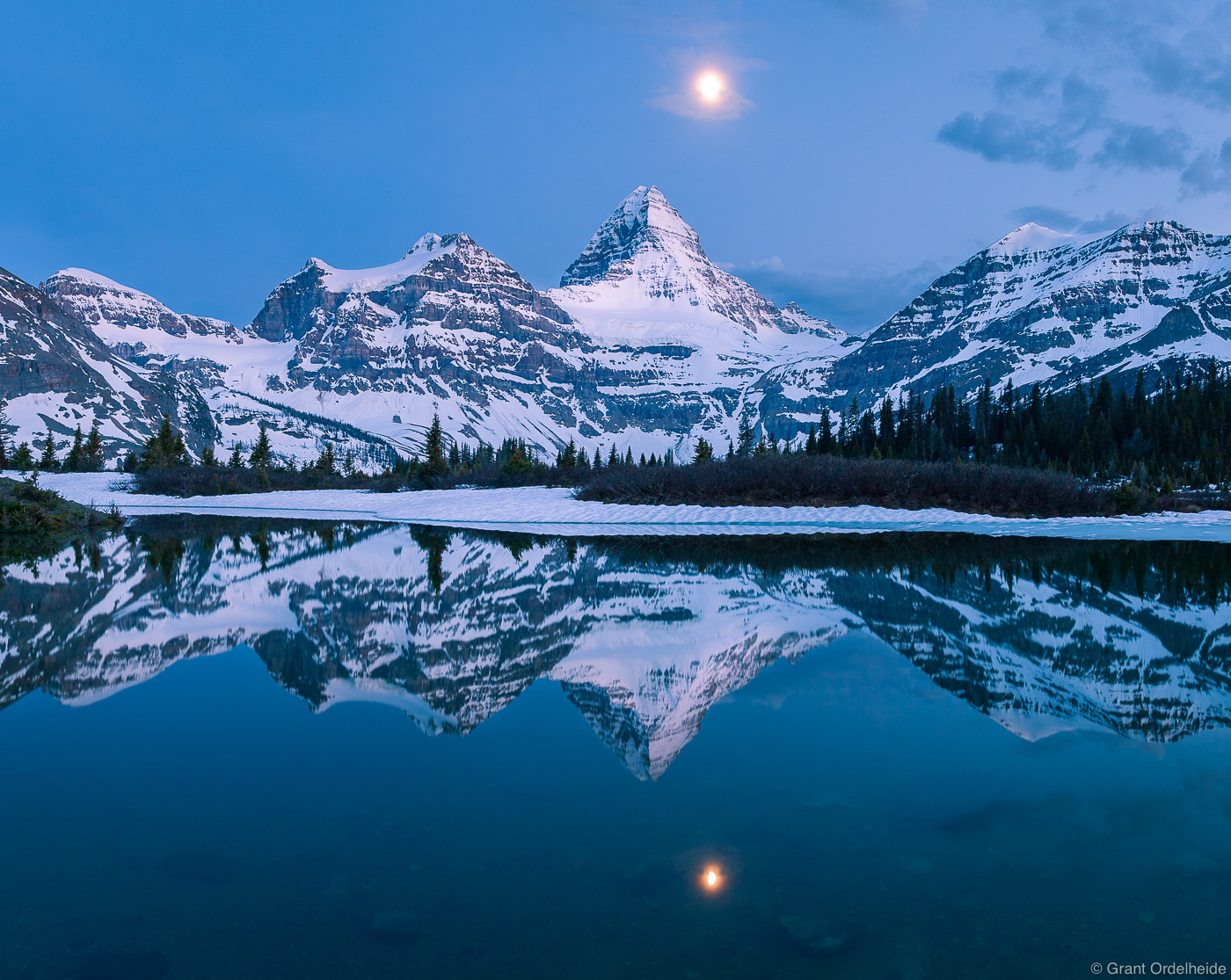 Mt. Assiniboine and the&nbsp;moon reflected in a small alpine tarn.