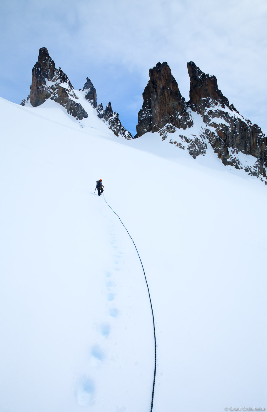 A rope team ascends an open snowfield below some remote spires in the Cerro Castillo National Reserve.